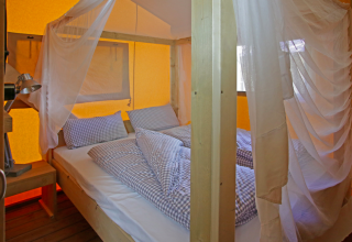Indvendigt billede af en Nature Lodge på Azur Camping Altmühle, Kipfenberg, med hyggelig seng og myggenet.