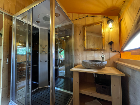 Salle de bain moderne avec douche en verre, vasque en pierre et miroir à Azur Camping Altmühle Nature Lodge.