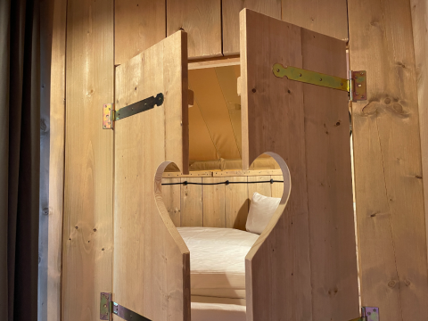 Cabane en bois avec ouverture en forme de cœur sur la porte, lit à l'intérieur, glamping Azur Camping Altmühle.