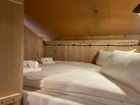 Gemütlicher Schlafbereich mit Doppelbett und Holzwänden in der Azur Camping Altmühle Nature Lodge.