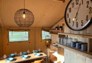 Innenansicht der gemütlichen Glamping-Unterkunft bei Azur Camping Altmühle mit Essbereich und großer Uhr.