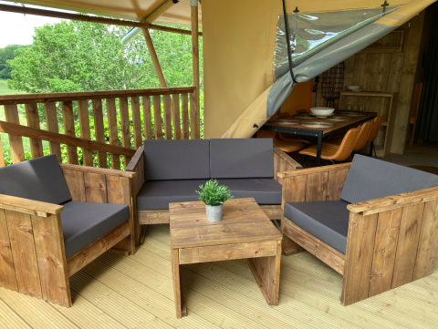 Udendørs opholdsområde på Azur Camping Altmühle Nature Lodge Beieren med træmøbler og grå hynder.