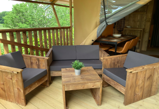 Area lounge esterna ad Azur Camping Altmühle Nature Lodge Beieren con arredi in legno e cuscini grigi.