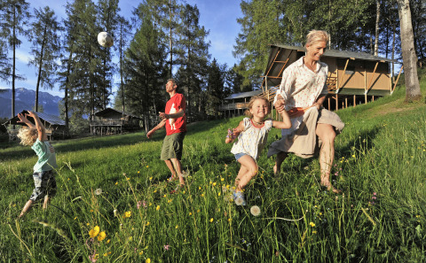 Familia disfruta al aire libre junto a lodges tipo safari en Nature Resort Natterer See, Tirol, Austria.