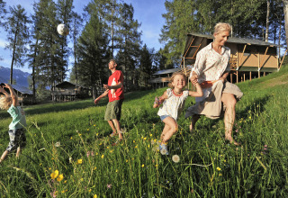Familie nyder en solrig dag og leger udendørs foran safaritelte på Nature Resort Natterer See i Tirol.