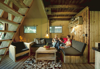 Gezin ontspant in een safarilodge van Nature Resort Natterer See - Safarilodges Tirol, gezellige houten stijl.