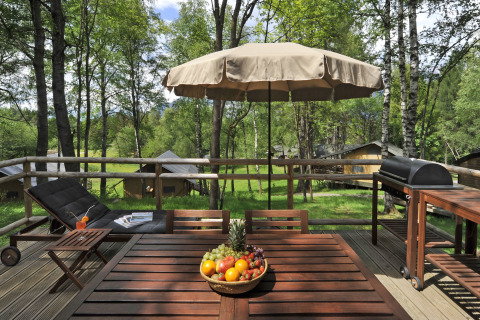 Terrazza in legno con tavolo, barbecue e lettino al Nature Resort Natterer See - Safarilodges Tirol immerso nel verde.