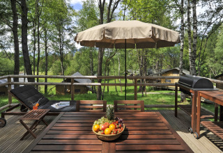Holzterrasse mit Esstisch, Grill und Liege im Naturresort Natterer See - Safarilodges Tirol in den Alpen.