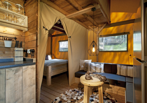 Cozy glamping accommodation at Nature Resort Natterer See Safarilodges Tirol with wooden interior and sofa.