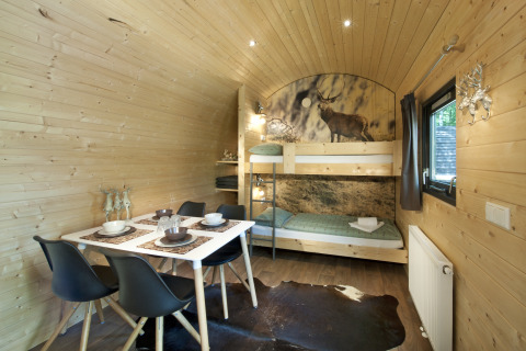 Interieurbeeld van een glamping accommodatie met stapelbed, eettafel en houthouten inrichting bij Nature Resort Natterer See.