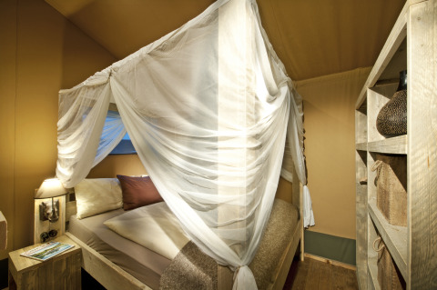 Interieur van een luxueuze safarilodge in Nature Resort Natterer See met hemelbed en houten meubilair.