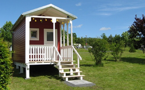 Alojamiento glamping en Camping Naumburg - Glamping Hessen con una pequeña cabaña roja en un prado verde.