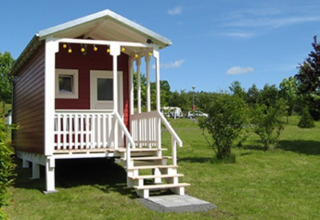 Glamping accommodatie bij Camping Naumburg - Glamping Hessen, kleine rode hut op een grasveld.