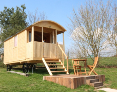 Glamping accommodatie met houten huisje op wielen, veranda en buitenterras bij Camping Naumburg, Hessen.