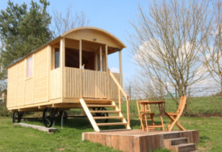 Alojamiento glamping con cabaña de madera sobre ruedas, porche y asientos exteriores en Hessen, Alemania.