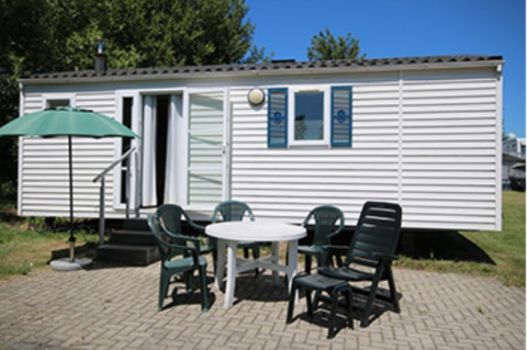 Moderne glampingbolig ved Camping Naumburg i Hessen med terrasse, plastikmøbler og parasol under blå himmel.