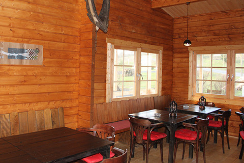 Interieur van een houten hut bij Camping Naumburg - Glamping Hessen met tafels, stoelen en grote ramen.