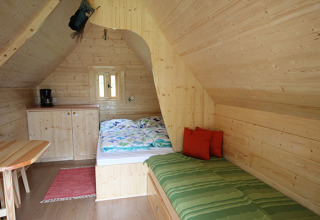 Knusse glamping accommodatie met houten interieur, bed en kitchenette bij Camping Naumburg - Glamping Hessen.
