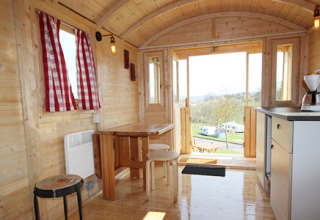 Indretning af hyggelig glamping-indkvartering på Camping Naumburg - Glamping Hessen med trævægge og rødrutede gardiner.