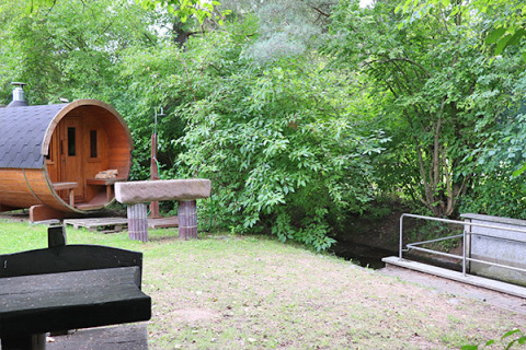 Alloggio glamping al Camping Naumburg in Assia, con una casetta a forma di botte accanto al verde lussureggiante.