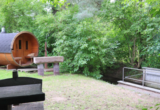 Alloggio glamping al Camping Naumburg in Assia, con una casetta a forma di botte accanto al verde lussureggiante.