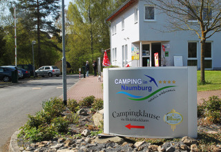 Ingresso del Camping Naumburg in Assia con un cartello che mostra il nome del campeggio e l’edificio principale.
