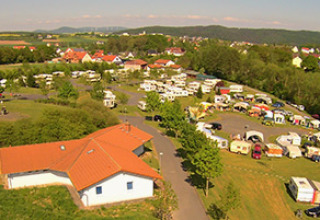 Aerial view of Camping Naumburg - Glamping Hessen with caravans, tents, and greenery in the countryside.