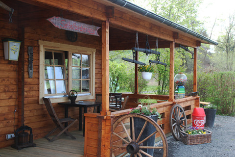 Véranda en bois décorée de fleurs et roues chez Camping Naumburg - Glamping Hessen, ambiance rustique.