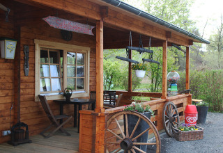 Veranda di legno con fiori e ruote al Camping Naumburg - Glamping Hessen, per un'esperienza glamping unica.