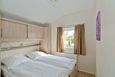 Slaapkamer in Landhuis Chalet op Campingpark Kerstgenshof, Duitsland, met tweepersoonsbed en raam.