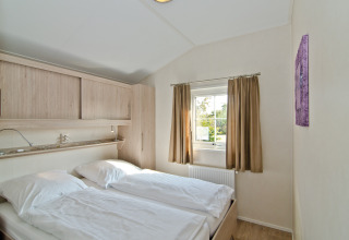 Bedroom in Landhuis Chalet at Campingpark Kerstgenshof, Germany, featuring double bed and window.