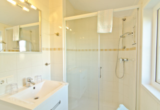 Bagno moderno e luminoso in sistemazione glamping presso Campingpark Kerstgenshof, con doccia e asciugamani.