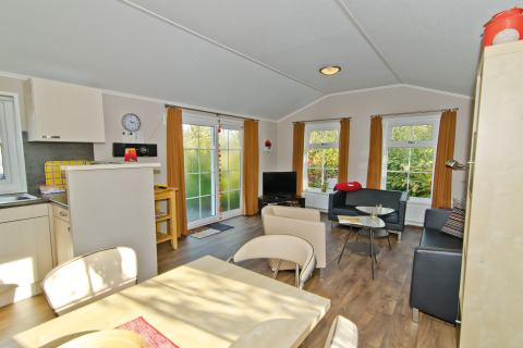 Vue intérieure du chalet Landhuis au Campingpark Kerstgenshof avec mobilier moderne et grandes fenêtres.