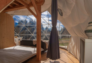 Interior of a glamping dome with wooden furnishings and large windows at Domaine la Chabanne, Auvergne-Rhône-Alpes.