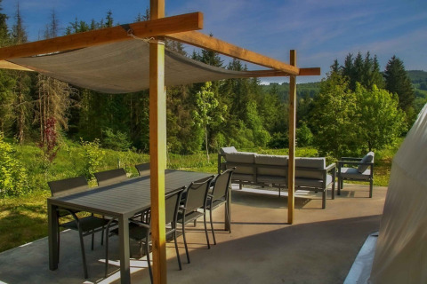 Udendørs terrasse med spisebord og sofaer omgivet af natur, Domaine la Chabanne - Domes Auvergne-Rhône-Alpes.