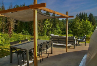 Terrasse mit Essbereich und Lounge-Möbeln inmitten grüner Natur, Domaine la Chabanne - Domes Auvergne-Rhône-Alpes.