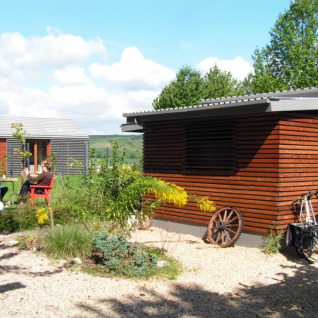 Moderne Glamping-Unterkunft im Campingpark Lindelgrund - Chalets Rheinland-Pfalz mit Gästen draußen.