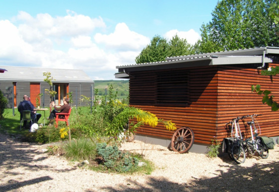 Modern glamping accommodation at Campingpark Lindelgrund - Chalets Rheinland-Pfalz with guests outdoors.