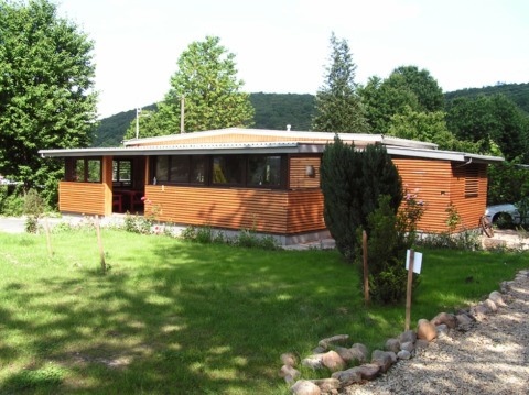 Modernes Holzchalet mit großen Fenstern in grüner Umgebung bei Campingpark Lindelgrund - Chalets Rheinland-Pfalz.