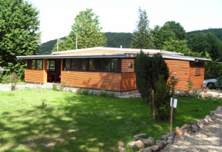 Chalet moderne en bois avec de grandes fenêtres entouré de verdure au Campingpark Lindelgrund - Chalets Rheinland-Pfalz.