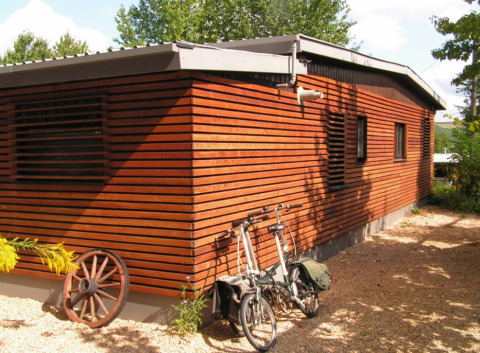 Et charmerende træchalet i Campingpark Lindelgrund med cykler og vogndel, Rheinland-Pfalz, Tyskland.