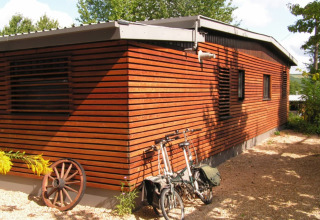 Et charmerende træchalet i Campingpark Lindelgrund med cykler og vogndel, Rheinland-Pfalz, Tyskland.