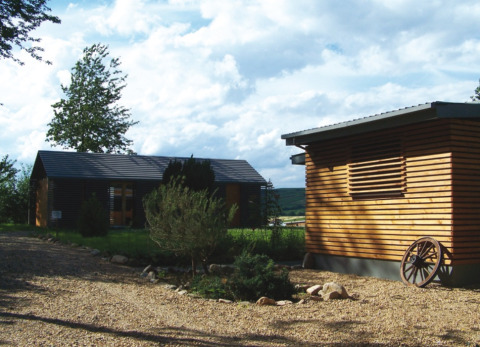 Moderne Holzchalets im Campingpark Lindelgrund, Rheinland-Pfalz, umgeben von Natur und Kieswegen.