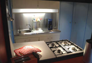 Pequeña cocina de glamping con estufa de gas, fregadero y cafetera en Campingpark Lindelgrund - Chalets Rheinland-Pfalz.