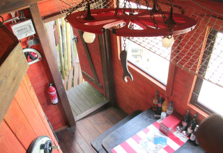 Interior of Erlebnisbahn Ratzeburg - Treinwagonhotel glamping with rustic wood decor, table, and drinks.