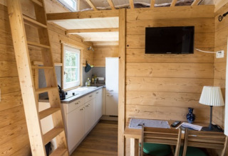 Interieur van Seecamping Appesbach Tiny House Oostenrijk met houten wanden, keuken en ladder.