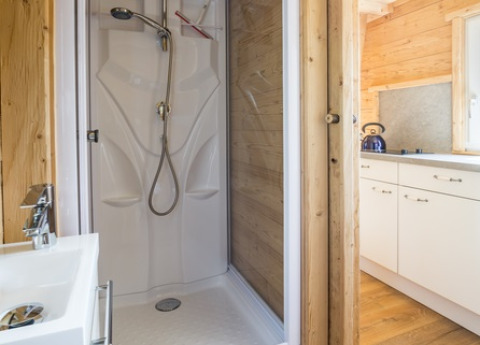 Moderne douchecabine en keuken in houten interieur bij Seecamping Appesbach - Tiny House Oostenrijk.