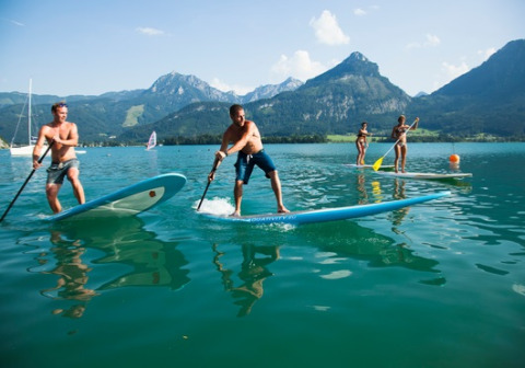 Personnes faisant du paddle sur un lac entouré de montagnes, près du Seecamping Appesbach - Tiny House Autriche.