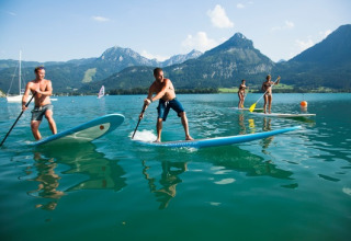 Personnes faisant du paddle sur un lac entouré de montagnes, près du Seecamping Appesbach - Tiny House Autriche.