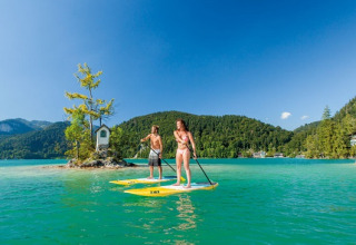 Deux personnes en paddle sur l'eau turquoise près de Seecamping Appesbach - Tiny House Autriche.